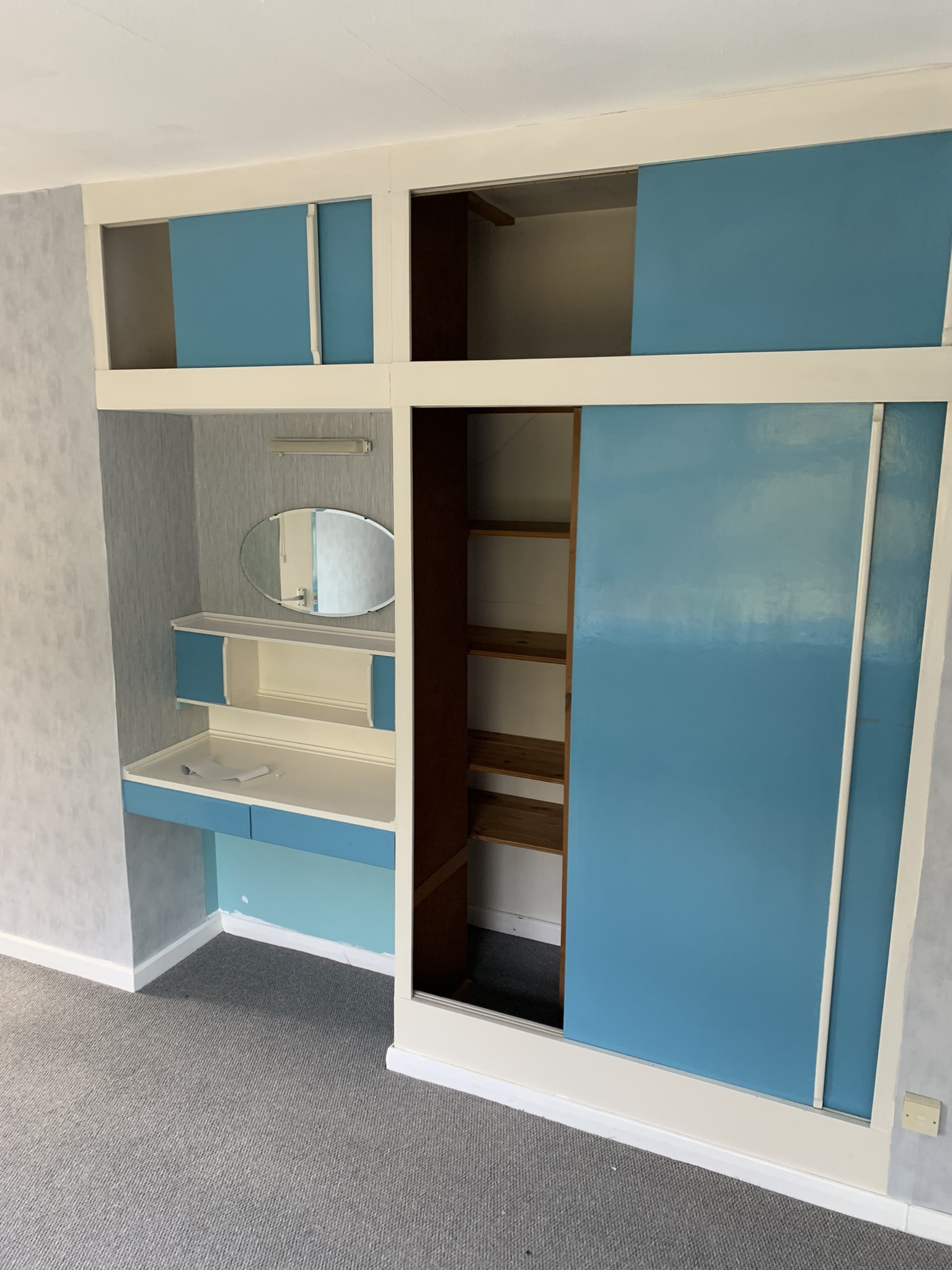 A view of a bedroom with a makeup table and blue wardrobe